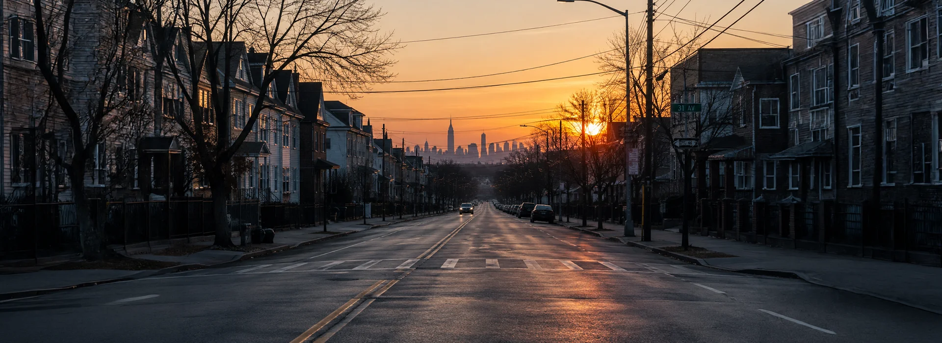 Quiet Queens residential street at dawn with the Manhattan skyline in the distance