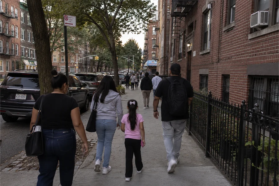 Latino family walking down a Bronx residential street lined with brick buildings