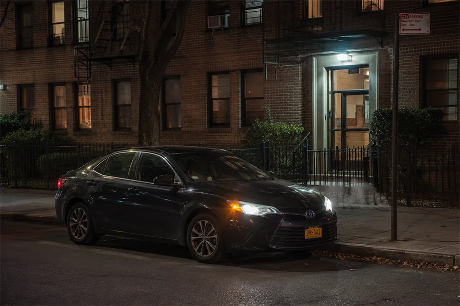 Dark sedan parked in front of a Bronx apartment building at night during a stakeout